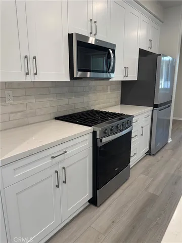a kitchen with cabinets stainless steel appliances and wooden floor