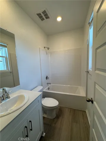 a bathroom with a granite countertop bathtub shower sink vanity mirror and toilet