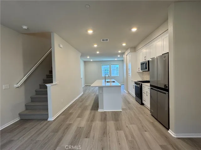 a view of kitchen with cabinets stainless steel appliances and wooden floor