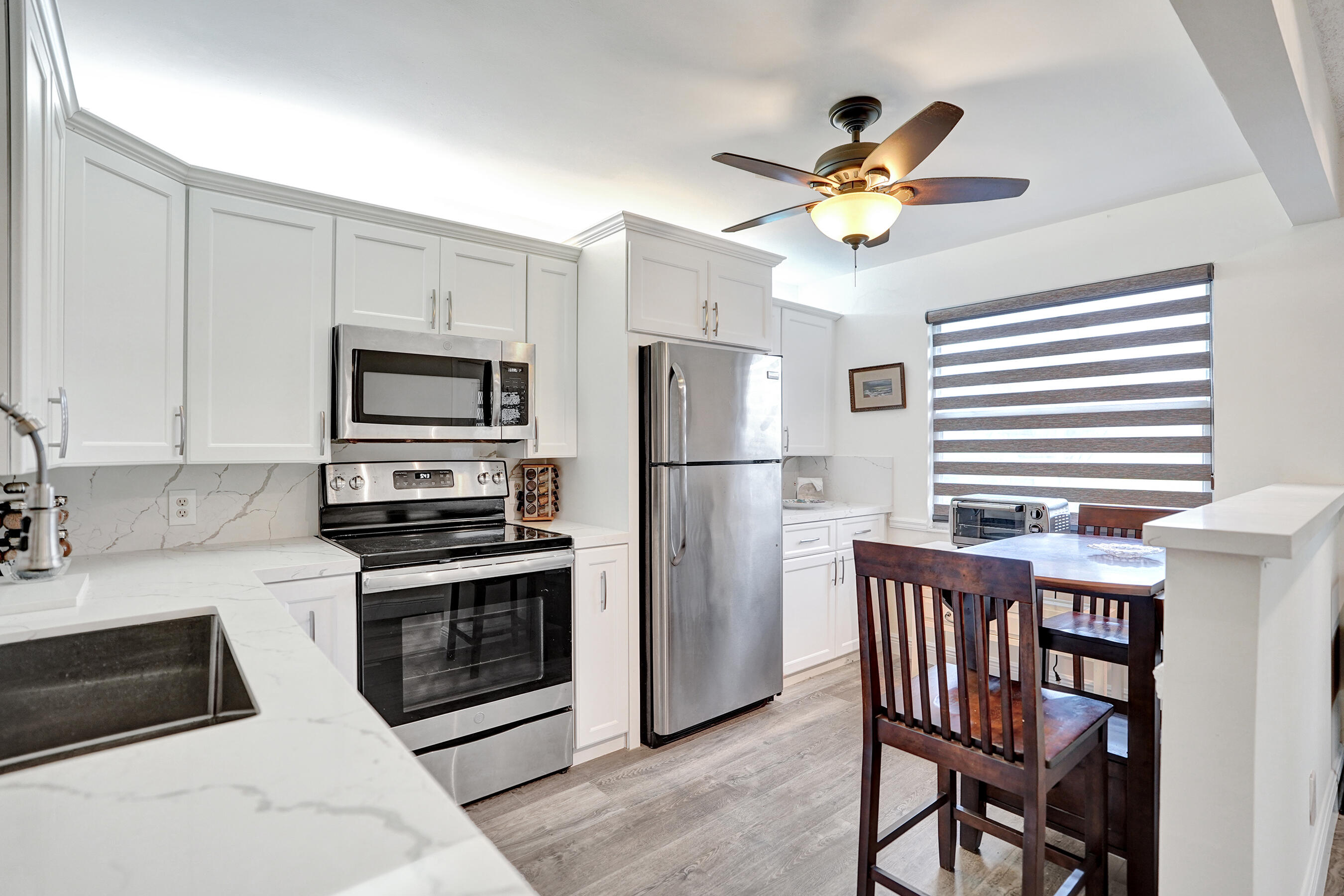 1033 Ainslie C Boca Raton, FL 33434 - Photo 5 of 42 a kitchen with stainless steel appliances a dining table chairs and a refrigerator