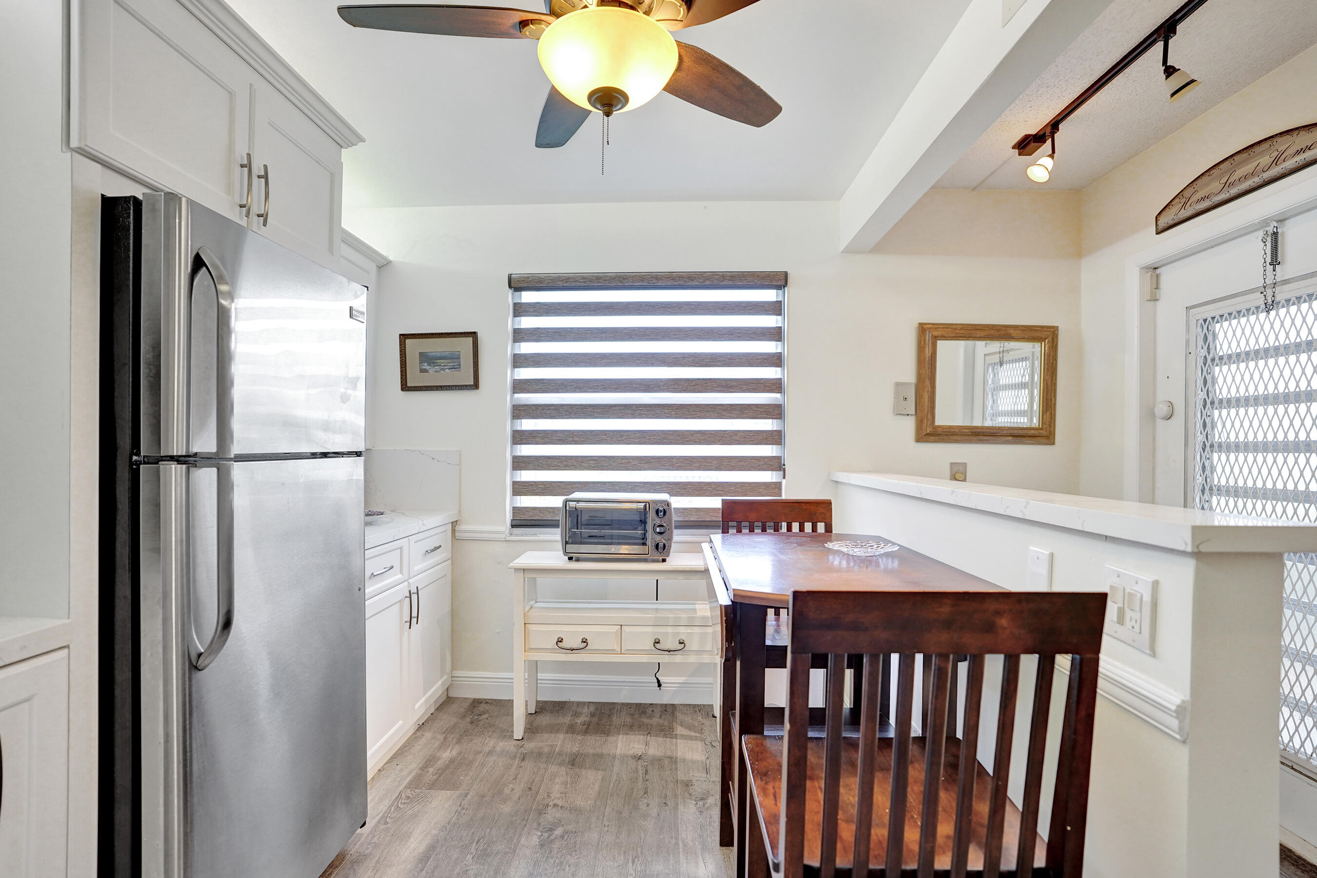 1033 Ainslie C Boca Raton, FL 33434 - Photo 6 of 42 a kitchen with stainless steel appliances granite countertop a refrigerator a sink dishwasher a stove and a dining table with wooden floor