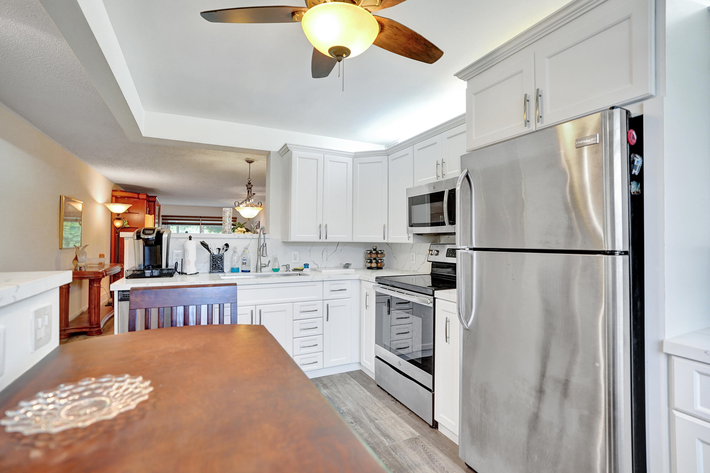 1033 Ainslie C Boca Raton, FL 33434 - Photo 7 of 42 a kitchen with stainless steel appliances granite countertop a refrigerator a oven a sink dishwasher and white cabinets with wooden floor