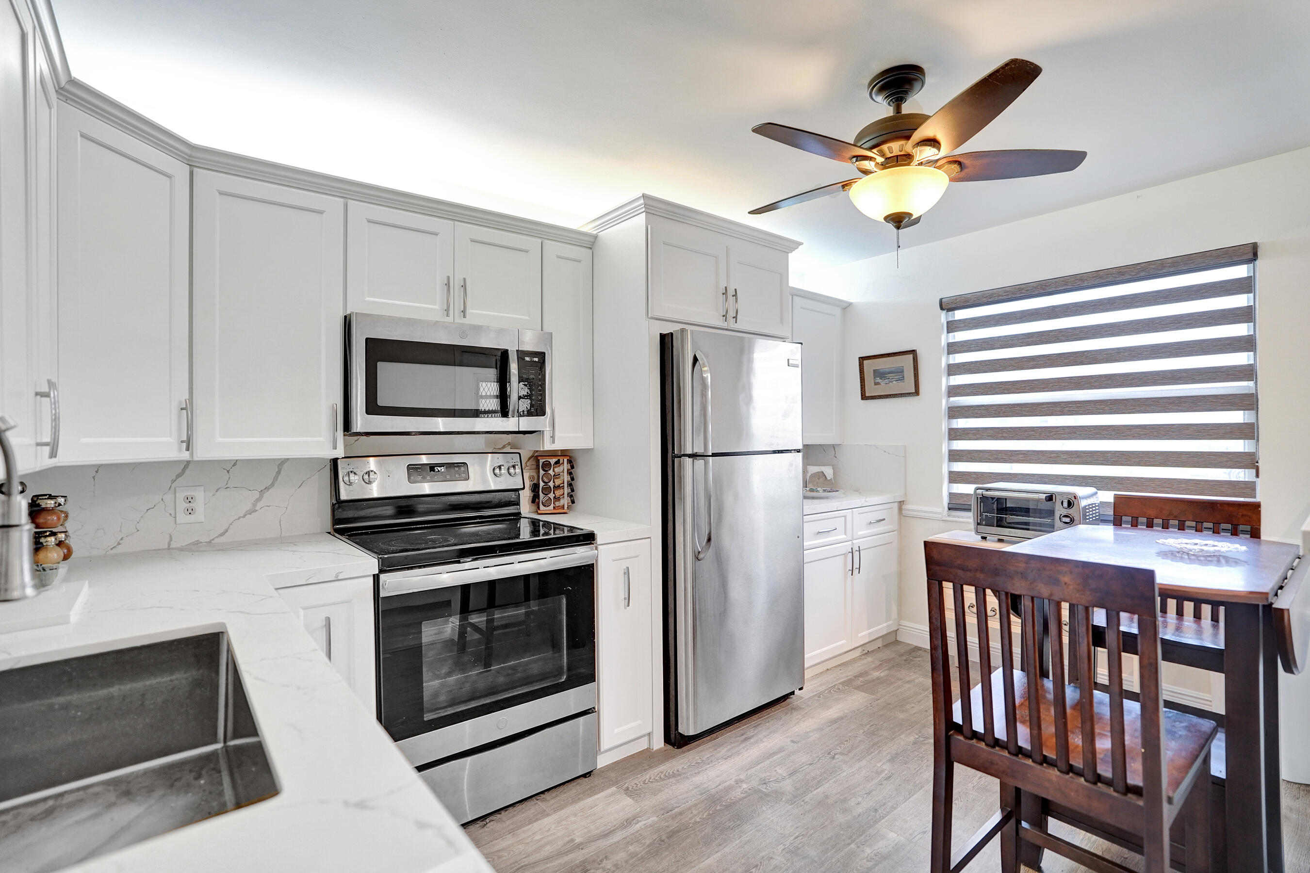 1033 Ainslie C Boca Raton, FL 33434 - Photo 10 of 42 a kitchen with stainless steel appliances granite countertop a stove a refrigerator a microwave a sink and white cabinets