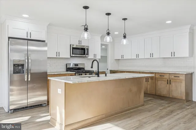 a kitchen with stainless steel appliances granite countertop a sink a stove and a wooden floors