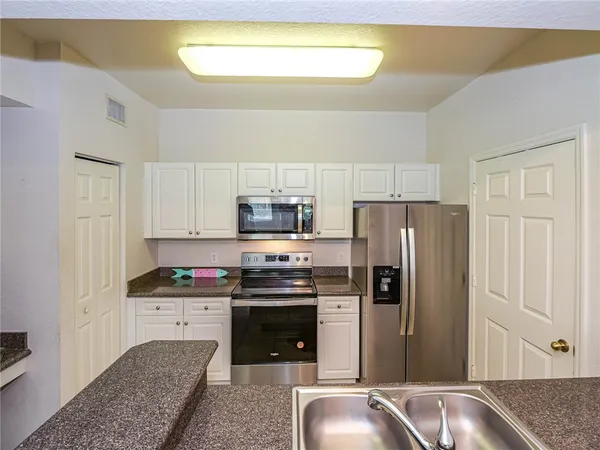 a kitchen with stainless steel appliances granite countertop a refrigerator sink and stove