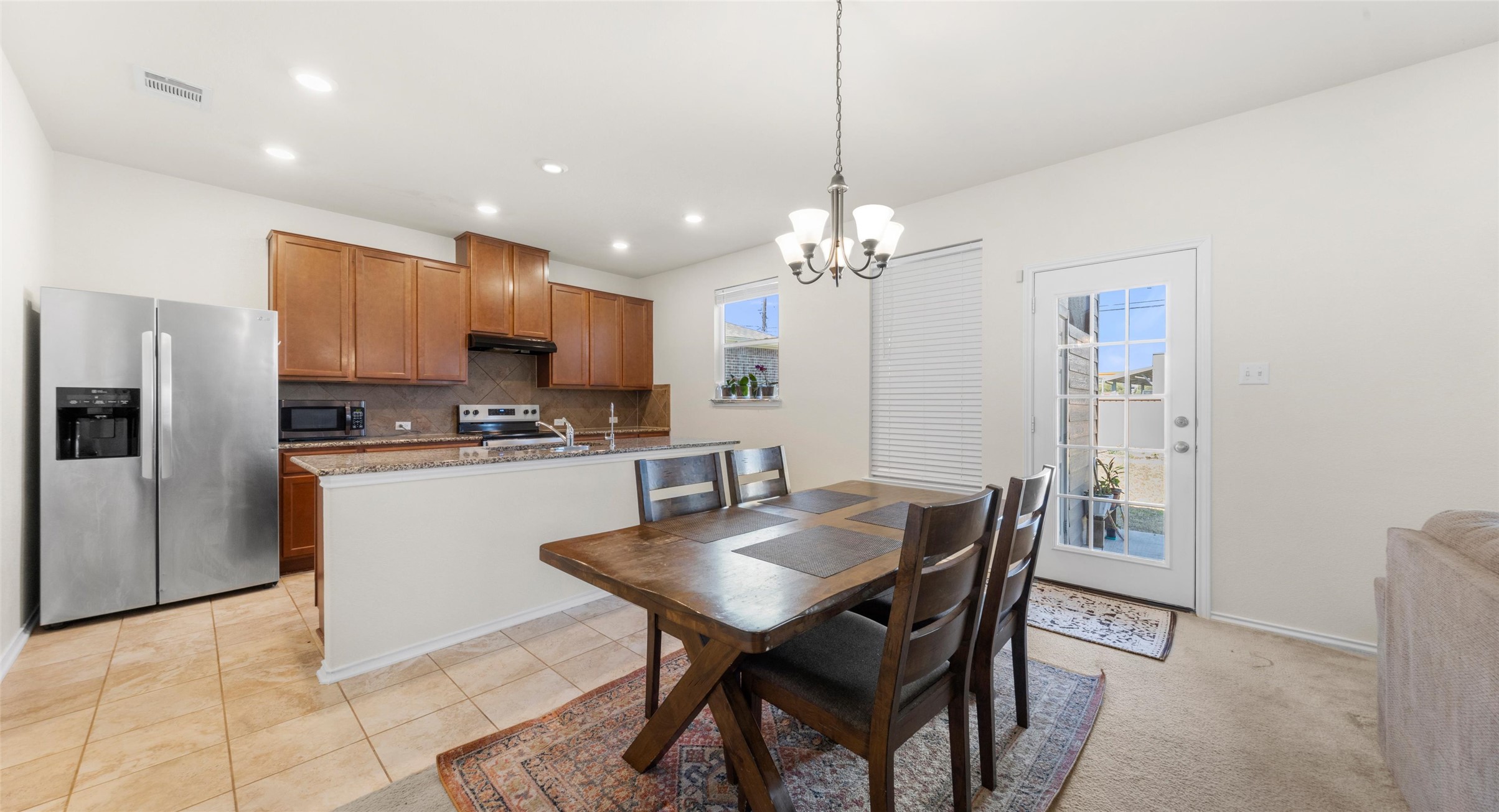 2471 Sunrise Road, Unit 2 Round Rock, TX 78664 - Photo 6 of 20 a kitchen with stainless steel appliances kitchen island granite countertop a refrigerator a stove a kitchen island a dining table and chairs with wooden floor