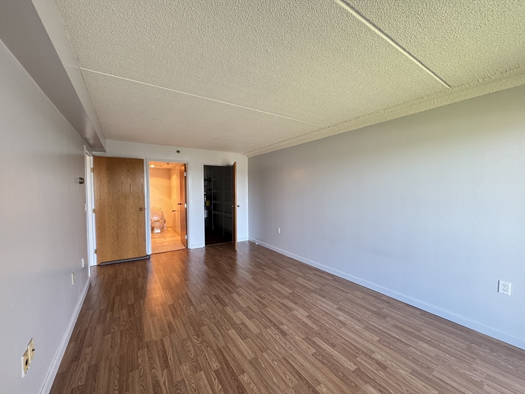 200 Cove Way, Unit 205 Quincy, MA 02169 - Photo 5 of 12 a view of an empty room with wooden floor and windows