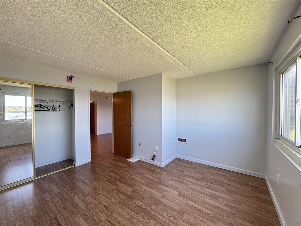 200 Cove Way, Unit 205 Quincy, MA 02169 - Photo 7 of 12 an empty room with wooden floor and windows