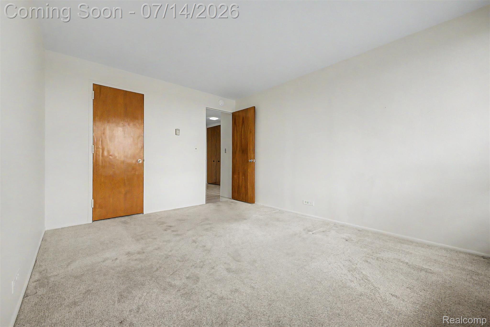 22700 Garrison Street, Unit 707 Dearborn, MI 48124 - Photo 12 of 22 Carpeted room featuring light neutral wall paint, two wood-paneled doors, and white baseboards