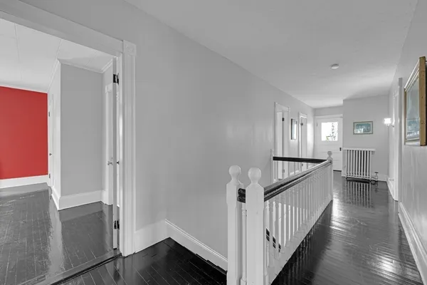 a view of a hallway with a white walls and wooden floor
