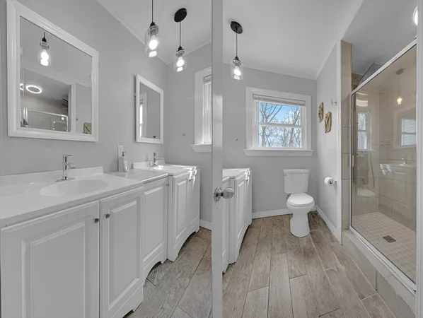 a spacious bathroom with a double vanity sink a toilet a shower and a mirror