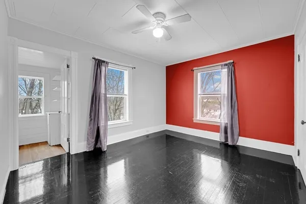 a view of an empty room with window and wooden floor