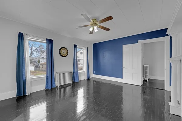 an empty room with wooden floor a ceiling fan and a window