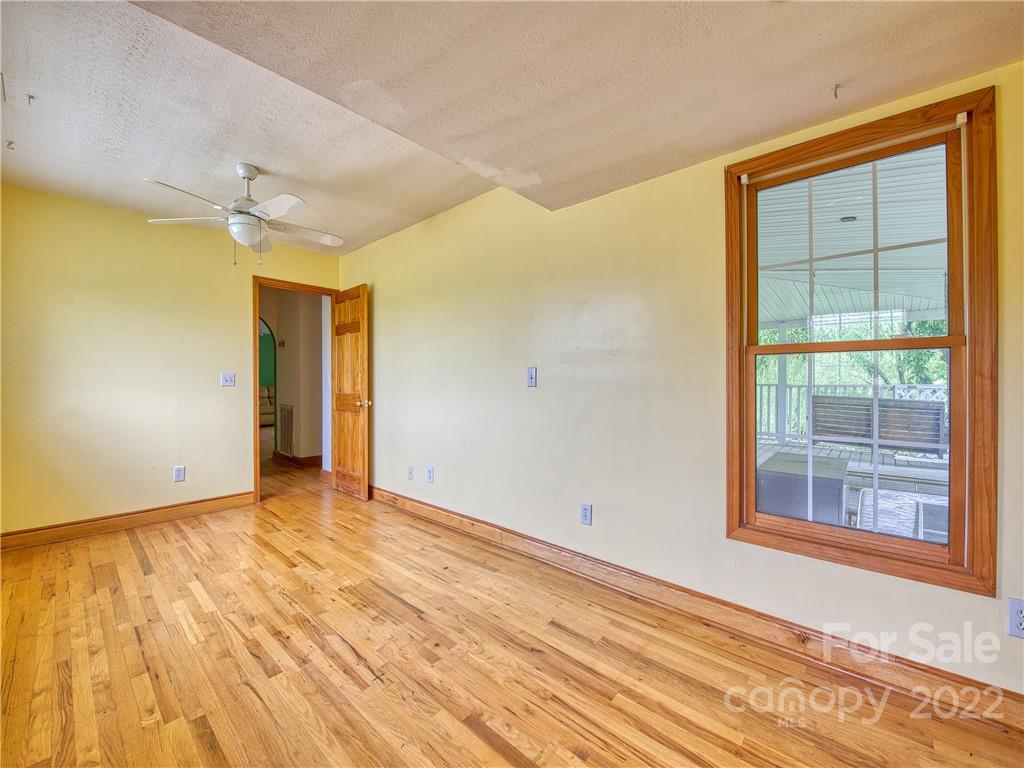 217 Durham Road Clyde, NC 28721 - Photo 21 of 24 a view of an empty room with wooden floor and a window