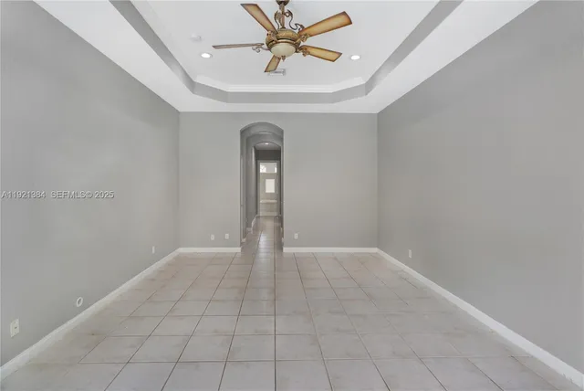 a view of an empty room with window and chandelier fan