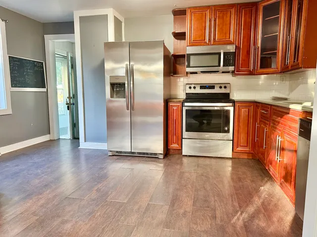 a kitchen with granite countertop a refrigerator and a stove top oven