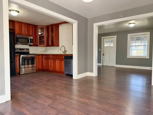 a view of kitchen with granite countertop stainless steel appliances and wooden floor