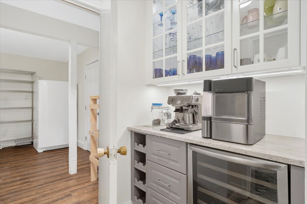 13126 Travis View Loop Austin, TX 78732 - Photo 11 of 27 Beverage bar area added in 2020 featuring beverage cooler, glass insert cabinets, dark wood-type flooring, freestanding refrigerator, and light stone counters