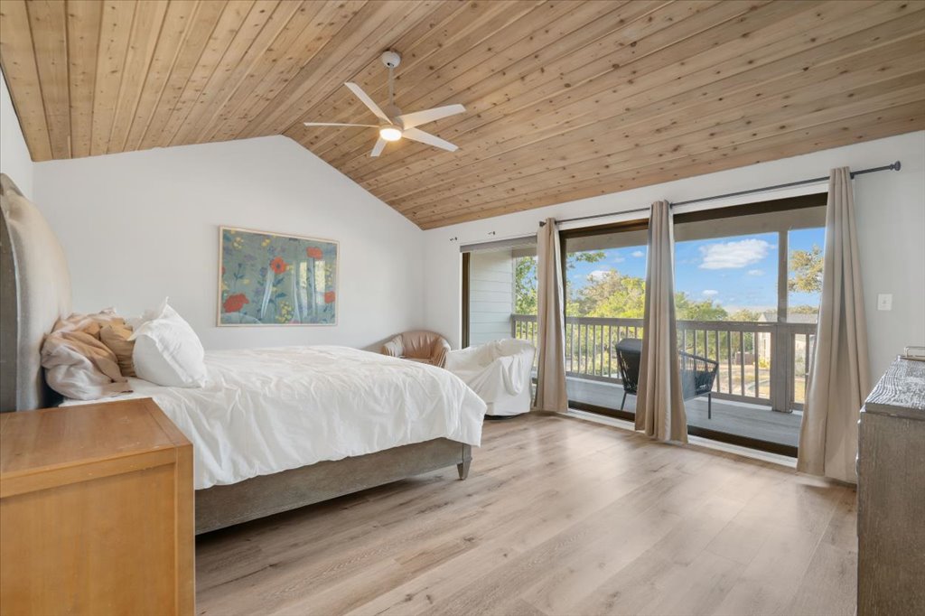 13126 Travis View Loop Austin, TX 78732 - Photo 13 of 27 Bedroom renovated in 2020 featuring access to outside, lofted ceiling, light wood-style floors, ceiling fan, and wood ceiling. Balcony view of the lake