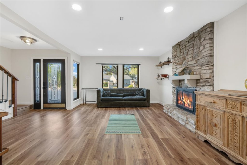 13126 Travis View Loop Austin, TX 78732 - Photo 6 of 27 Living room view from eating area with stairs, light wood-style flooring updated in 2020, recessed lighting, and a stone fireplace