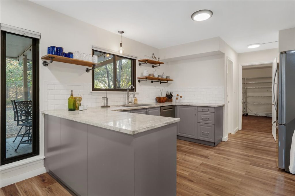 13126 Travis View Loop Austin, TX 78732 - Photo 7 of 27 Updated in 2020 Kitchen featuring quartz countertops, a peninsula, decorative light fixtures, tasteful backsplash, gray cabinetry, and light wood finished floors