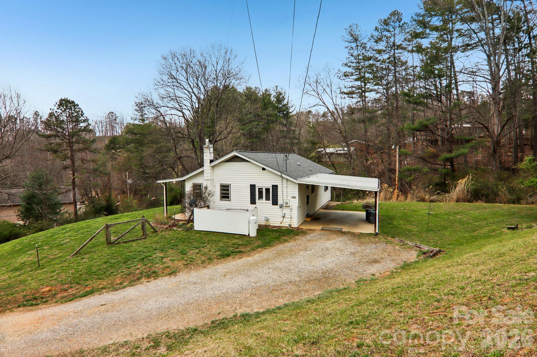 105 Baird Road Mars Hill, NC 28754 - Photo 2 of 48 a house that is sitting in the grass with large trees and wooden fence