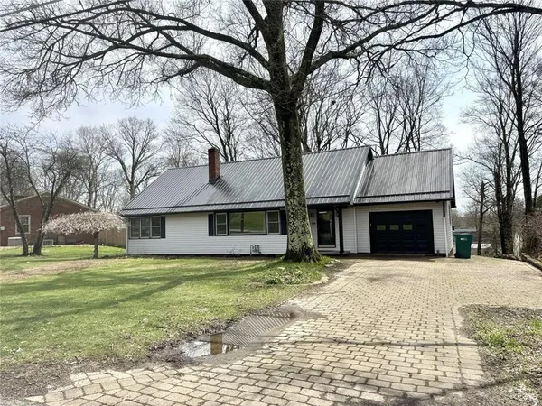a front view of a house with a yard and trees