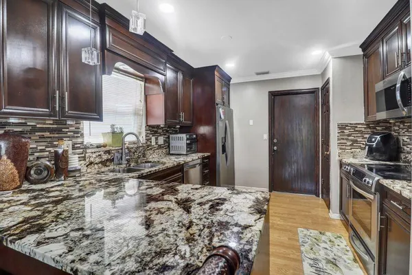 a kitchen with stainless steel appliances kitchen island granite countertop a sink stove and refrigerator
