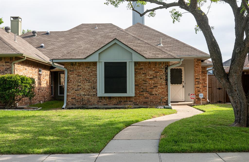 2028 Falcon Ridge Drive, Unit B Carrollton, TX 75010 - Photo 1 of 11 Ranch-style house with a front lawn, roof with shingles, and brick siding