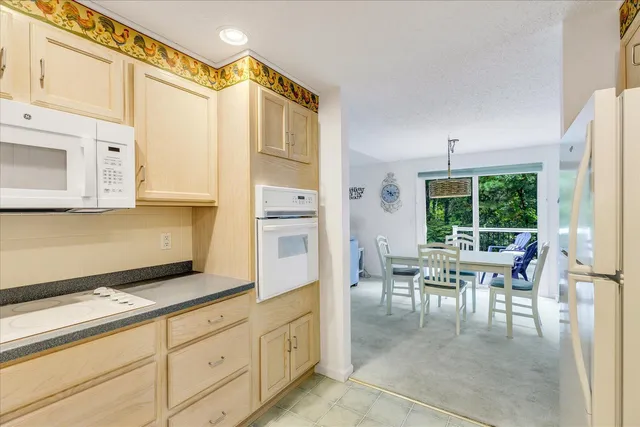 a dining hall with stainless steel appliances granite countertop a stove a sink a dining table and chairs with wooden floor