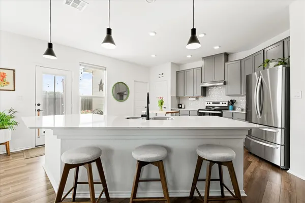 a kitchen with stainless steel appliances granite countertop a sink a stove a refrigerator and island with wooden floor