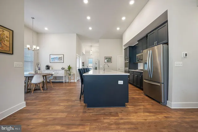 a kitchen with stainless steel appliances granite countertop a refrigerator a sink dishwasher a oven with white cabinets and wooden floor