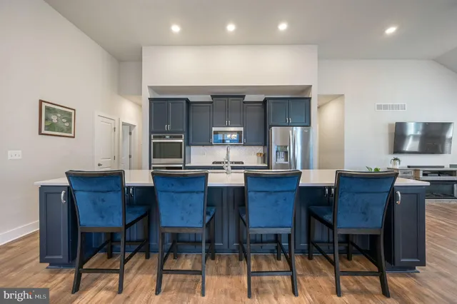 a kitchen with stainless steel appliances kitchen island granite countertop a table chairs microwave and sink