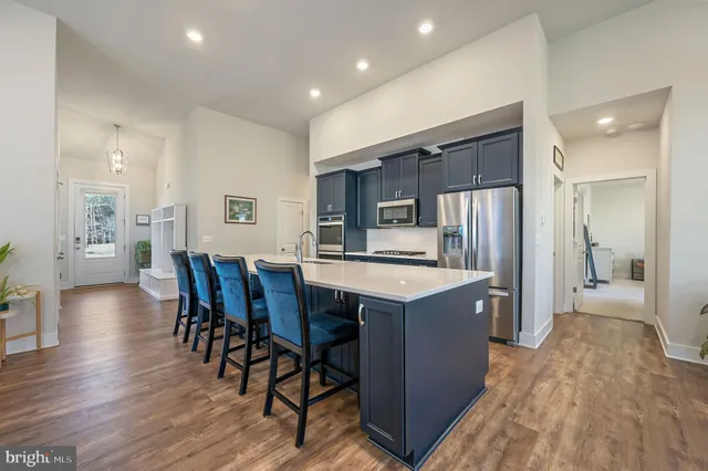 a kitchen with stainless steel appliances granite countertop a kitchen island a stove a refrigerator a sink a dining table and chairs