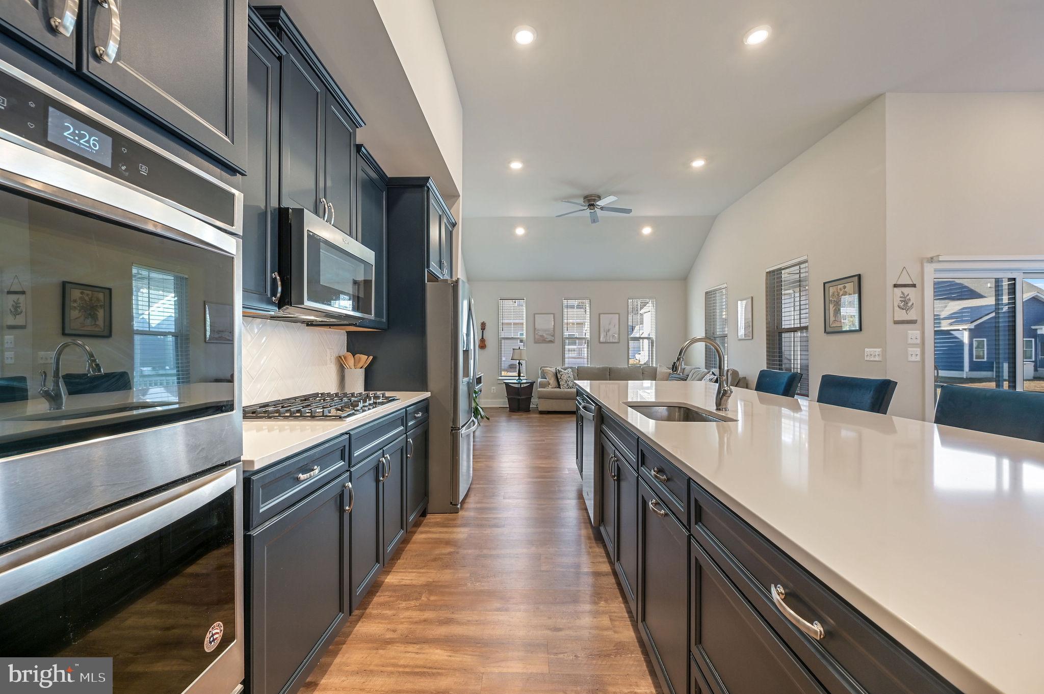 18556 Emerson Way Georgetown, DE 19947 - Photo 9 of 30 a large kitchen with stainless steel appliances lots of counter space and wooden floor
