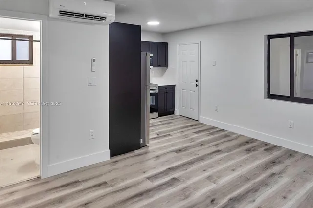 a view of a hallway with wooden floor and a bathroom