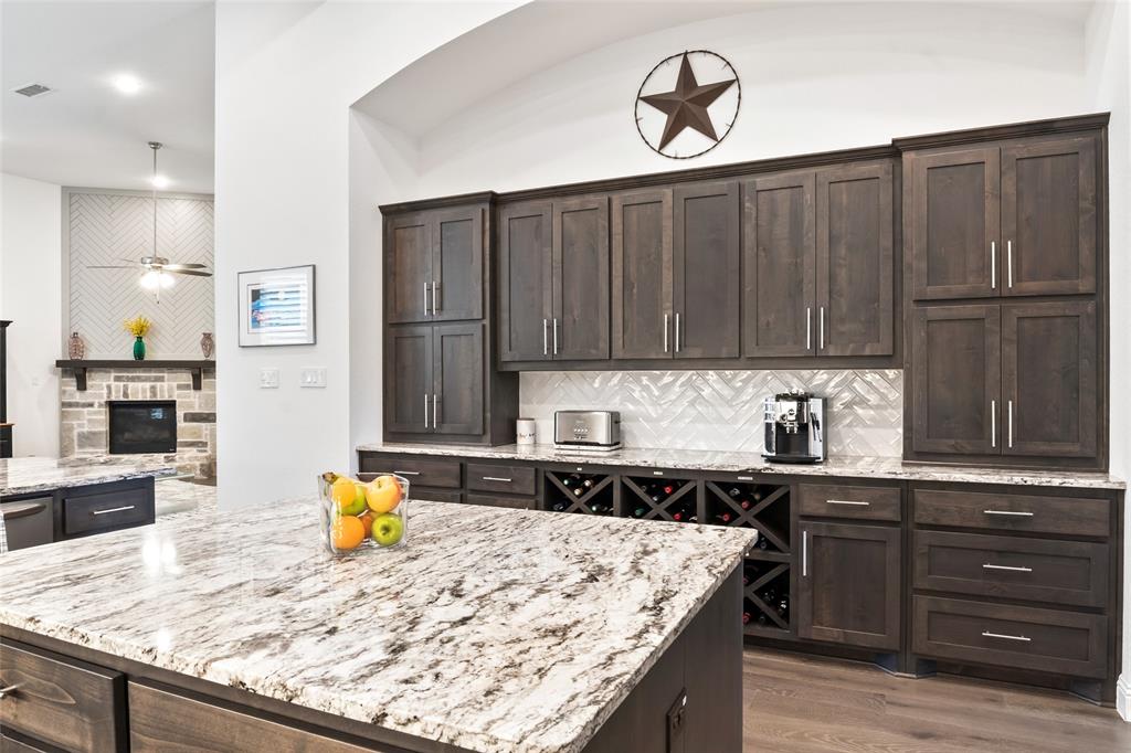 2109 Georgetown Boulevard Prosper, TX 75078 - Photo 6 of 40 a kitchen with granite countertop a sink a stove and wooden cabinets