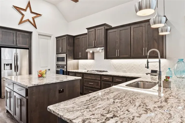 a kitchen with stainless steel appliances granite countertop a sink stove and refrigerator