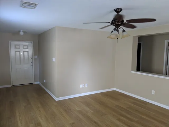 a view of a room with wooden floor and ceiling fan