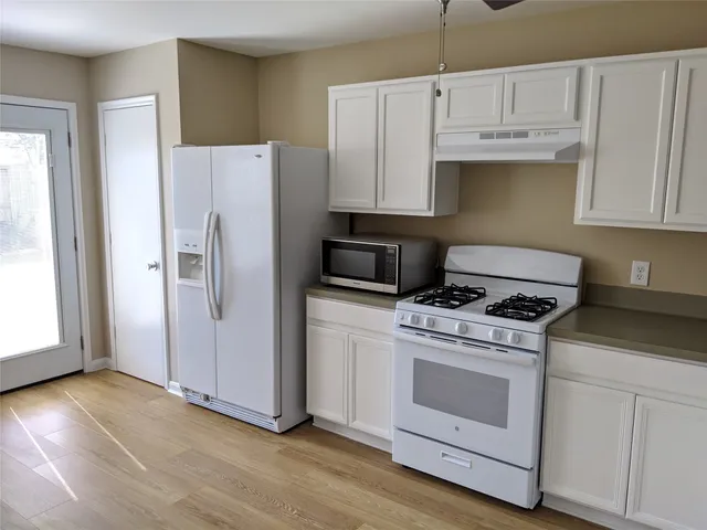 a kitchen with white cabinets and white appliances