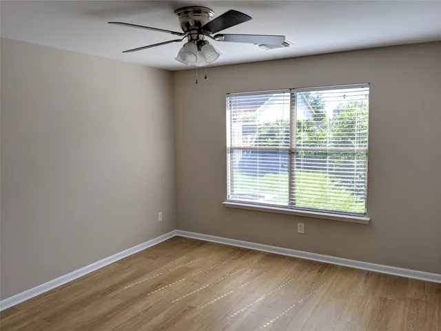 a view of an empty room with a window and wooden floor