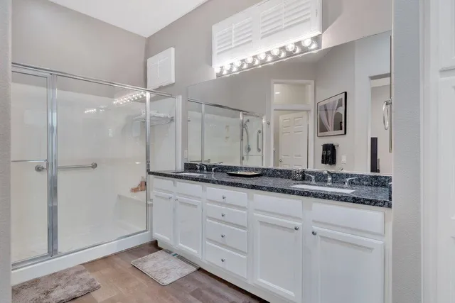 a bathroom with a granite countertop sink a mirror and a shower