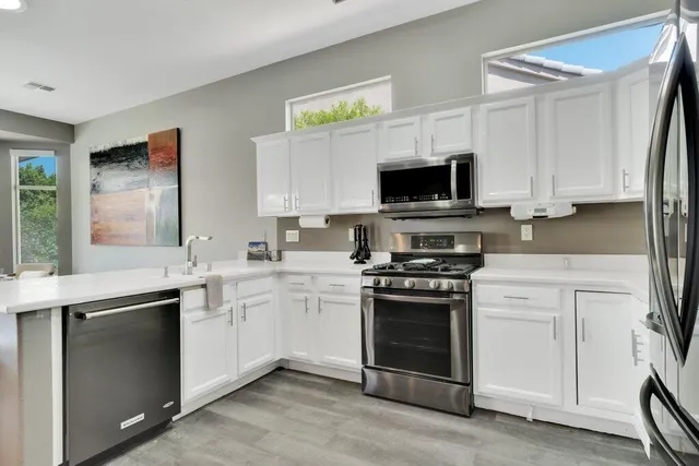 a kitchen with stainless steel appliances granite countertop a stove top oven a sink and a microwave