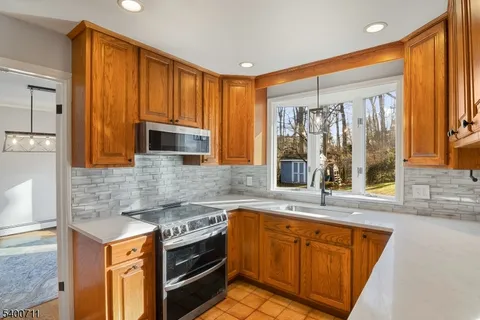 a kitchen with stainless steel appliances granite countertop wooden cabinets a sink and a large window