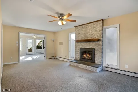 a view of a livingroom with a fireplace a ceiling fan and a fireplace