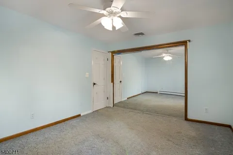 a view of an empty room and chandelier fan