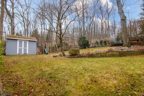 a backyard of a house with large trees and wooden fence