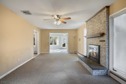 a view of a livingroom with a fireplace a ceiling fan windows and closet