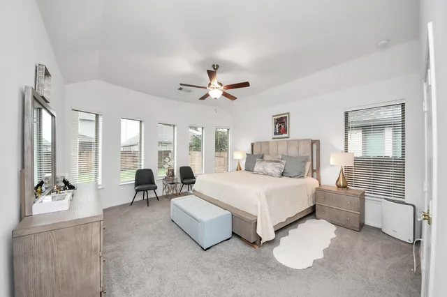 a spacious bedroom with a bed couch and large windows