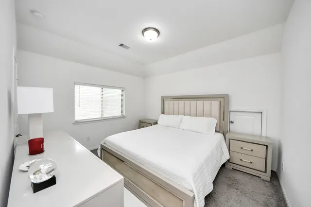 a large white bed sitting in a room next to a window and a chandelier